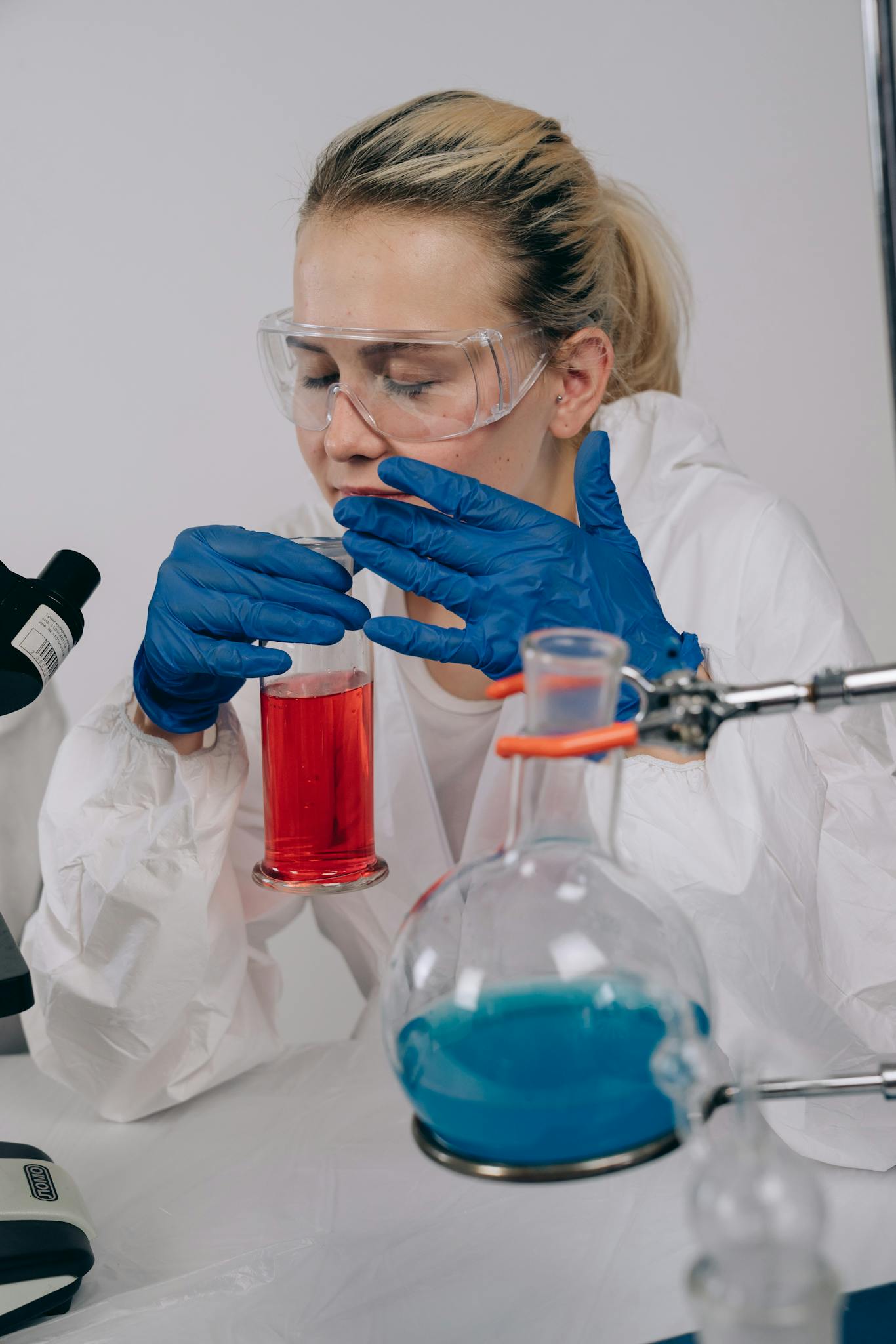 Scientist in protective gear conducting an experiment with colored chemicals in a lab.